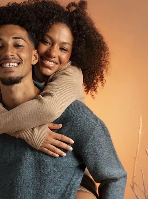 Un couple complice, la femme sur le dos de son compagnon, tous deux souriants