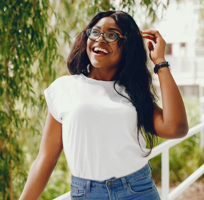 Jeune femme souriante, à l'extérieur, regardant au loin